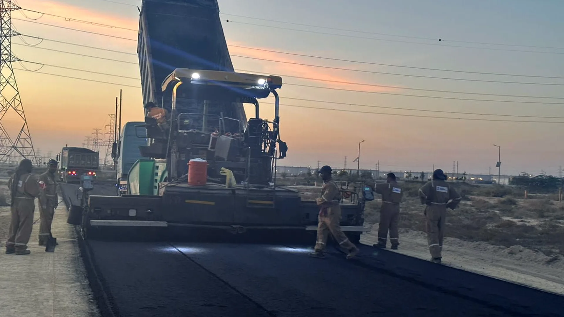 East Hope Contracting crew laying asphalt at dusk on a road project in Ras Tanura, Eastern Province